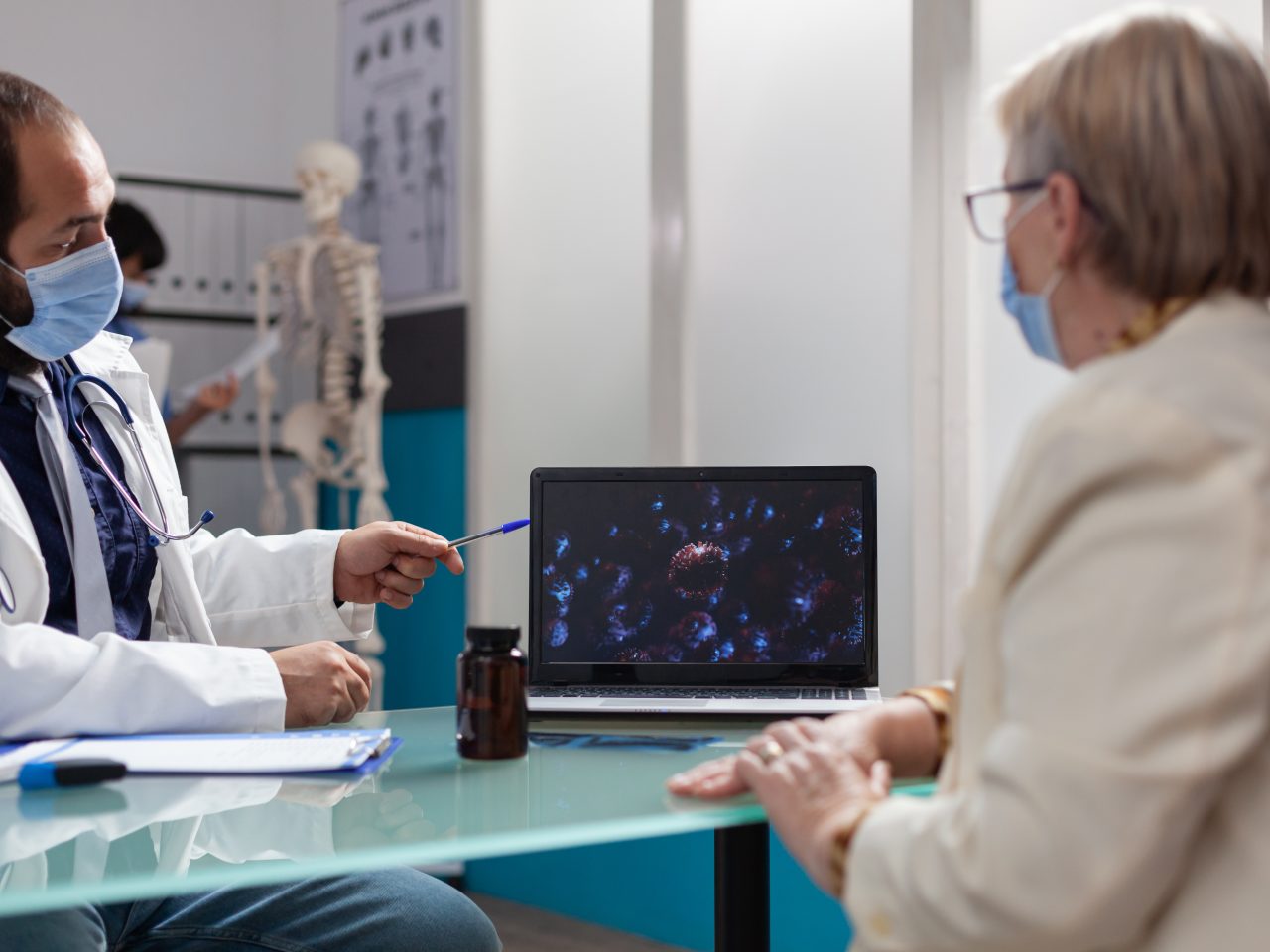 Specialist and patient looking at virus presentation on laptop